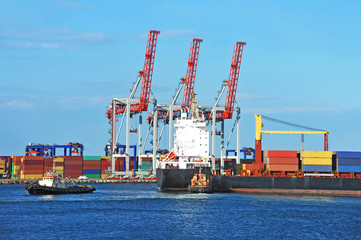 Tugboat assisting container cargo ship