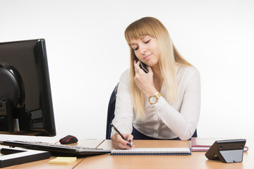 Secretary writing in a notebook information received by phone