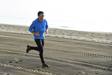 young sport man running alone on desert beach along the sea shore training workout