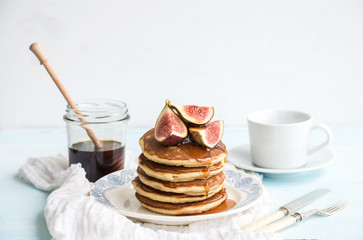 Fototapeta na wymiar Pancake tower with fresh figs and honey on a rustic plate. White background