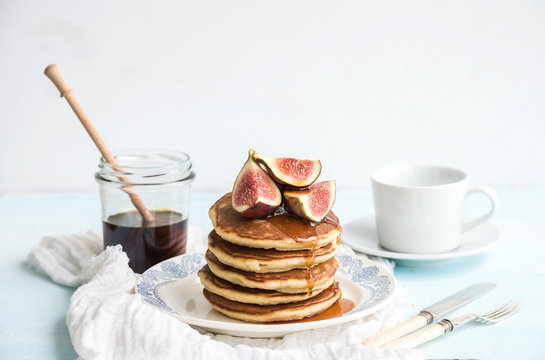 Pancake tower with fresh figs and honey on a rustic plate. White background