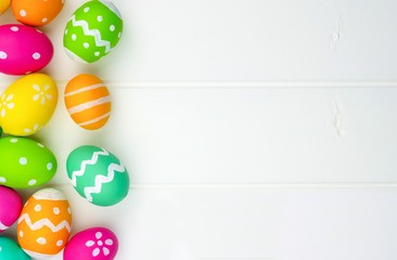 Fototapeta na wymiar Colorful Easter egg side border against a white wood background