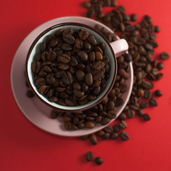Cup of coffee beans on a red background