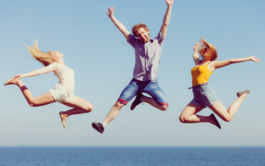 Group of friends boy two girls jumping outdoor