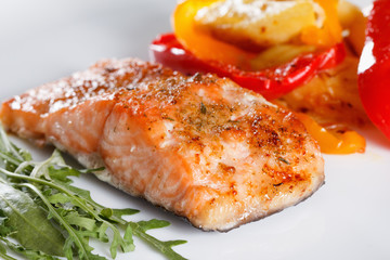 Grilled salmon fillet with vegetables, spices and arugula on a plate
