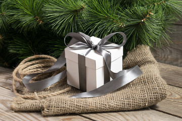 Fototapeta na wymiar white gift box with grey ribbons, cristmas tree branch and rope