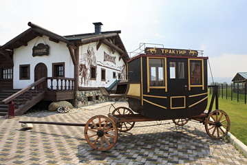 Fototapeta premium Vintage stagecoach and Restaurant Tavern Dillizhans. Tourist Complex Siberian Podvorye.