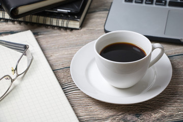 Working desk with coffee laptop glasses book notepad supplies and tablet  on wooden desk