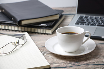 Working desk with coffee laptop glasses book notepad supplies and tablet  on wooden desk