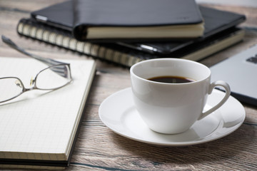Working desk with coffee laptop glasses book notepad supplies and tablet  on wooden desk