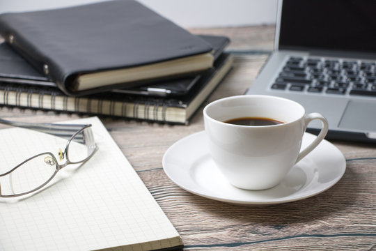 Working desk with coffee laptop glasses book notepad supplies and tablet  on wooden desk