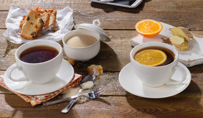 Cups of tea with sweet cake and orange