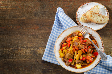 Meat stew with vegetables on rustic wooden table.