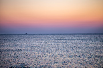 Fototapeta premium Schiff am Horizont vor pastellfarbenem Sonnenaufgang 