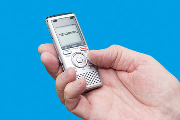 Elderly man is holding voice recorder on blue background, color and contrast manipulated