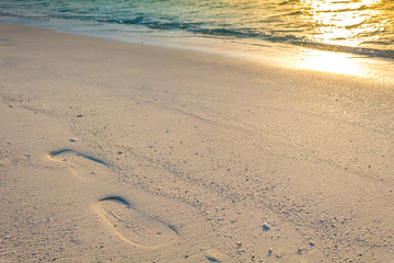 Footprints in the sand at Maldives with reflected sun