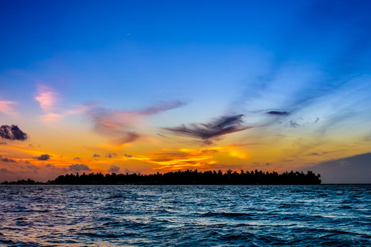 Silhouette of a maldivian island in sunset from ocean