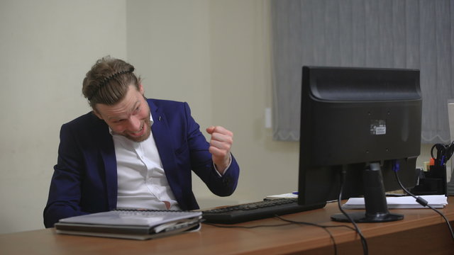 Active businessman rejoices success. In the office, sitting at the computer
