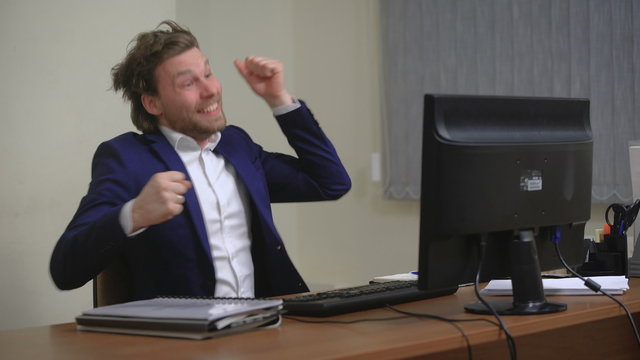 Active businessman rejoices success. In the office, sitting at the computer