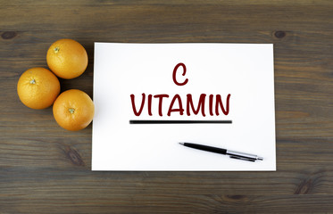 Wooden background with oranges and text: C VITAMIN