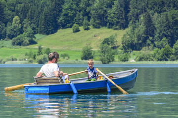 Fototapeta na wymiar kleiner Junge rudert mit den Eltern über den See