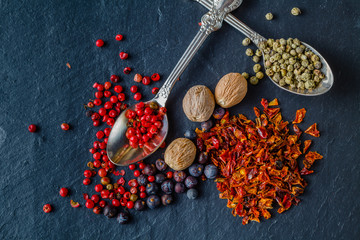 Various spices in old metal spoons on a stone background
