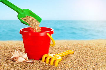Baby toy bucket, shovel and rake in the sand.