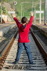 Young hitchhiker waiting of the train, standing on railway