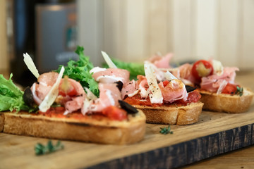 Slices of prosciutto rolled up and arranged on a lettuce leaf.