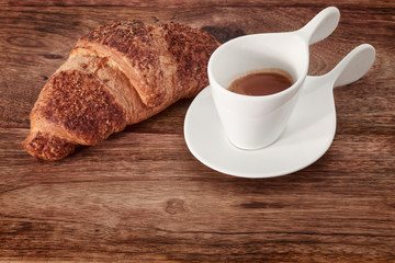 cup of coffee and croissant on wood
