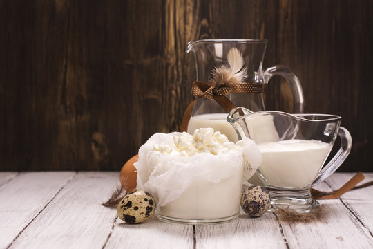 Organic dairy products (milk, sour cream, cottage cheese) and fresh hen and quail's eggs over wooden background. Rustic style. Selective focus
