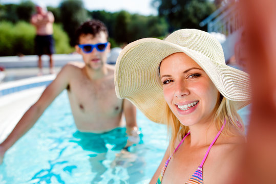 Couple in the swimming pool taking selfie. Summer and water.