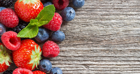 wooden background with fresh berries and mint, top view