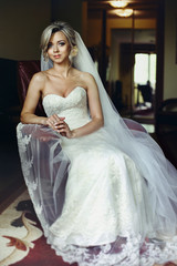 Naklejka premium Beautiful, stylish blonde bride posing on leather chair