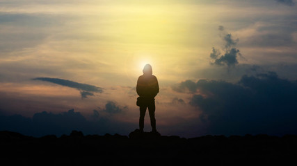The silhouette of a man holding a camera watching the sunset.