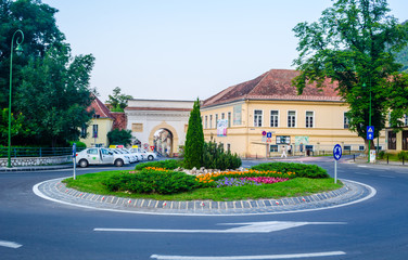 view of a small roundabout with an ancient poarta schei gate leading to the old town of romanian...
