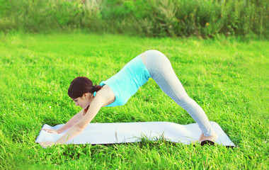 Fototapeta premium Woman doing yoga exercises on grass in summer day