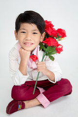 Little Asian boy in vintage suit with red rose