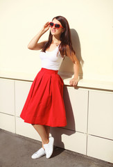 Beautiful brunette woman wearing a sunglasses and red skirt in c