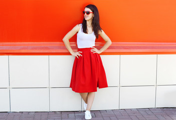 Beautiful brunette woman wearing a sunglasses and red skirt in c