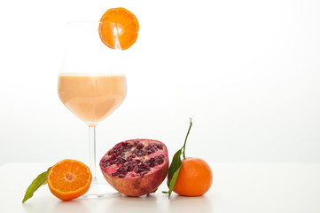 Healthy orange, pomegranate and kefir yogurt smoothie milkshake. Served with fresh sliced orange and whole pomegranate. Isolated on white background.