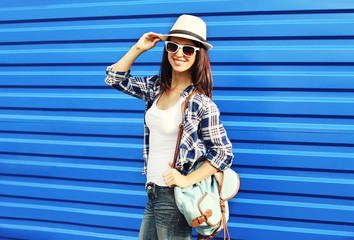 Pretty smiling woman wearing a straw hat, sunglasses and backpac