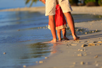 father and little daughter walking on beach
