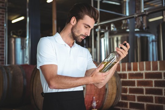 Winemaker examining bottle of white wine