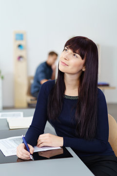 frau im büro schaut nachdenklich nach oben