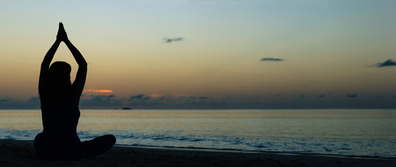 young woman doing yoga on sunset beach