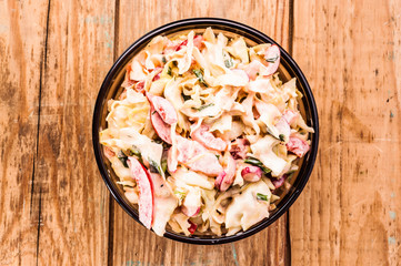 Vegetable salad with sauce in bowl on wood background