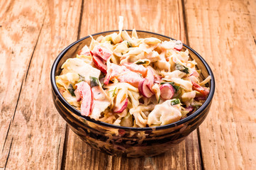 Vegetable salad with sauce in bowl on wood background