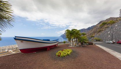 Fototapeta na wymiar Restored fishing boat, behind the rock group los Gigantes in Puerto de Santiago, Tenerife, Canary Islands, Spain, Europe