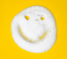 Smiley of soap suds on yellow background